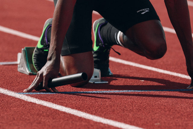 Athlete in sprint starting position on red running track