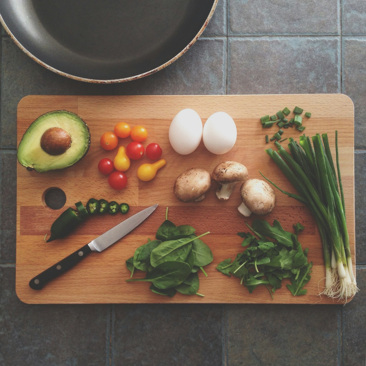 Fresh vegetables, avocado, eggs, and mushrooms on a cutting board — whole-food meal prep supporting metabolic health