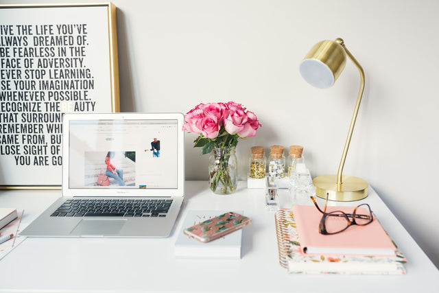 Laptop beside a desk lamp and notebooks