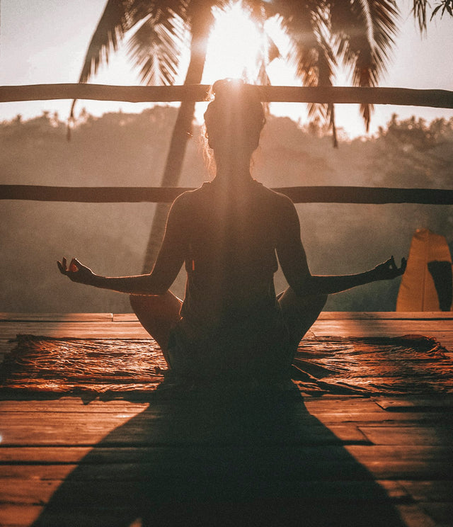 Person practicing yoga outdoors at sunrise