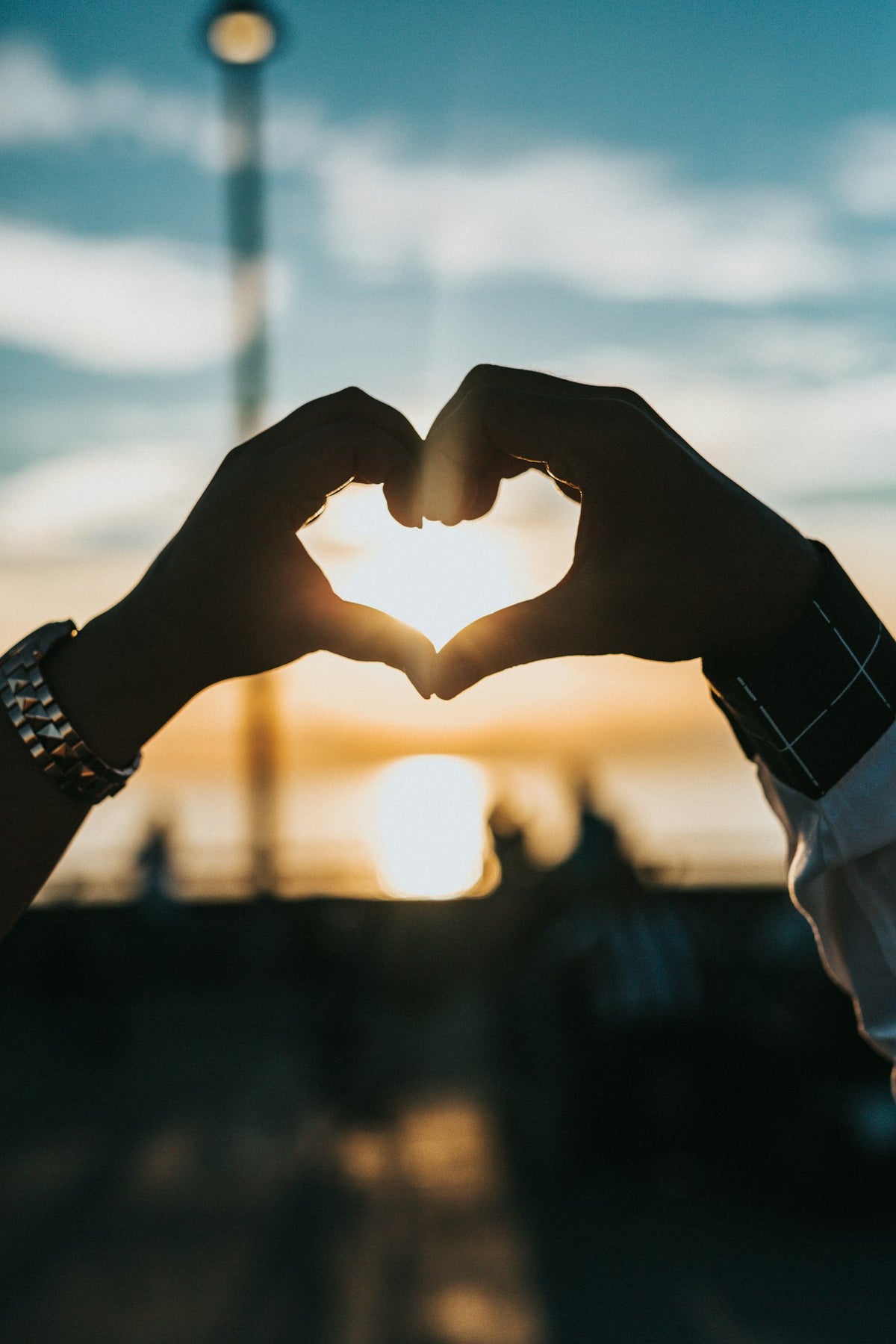 Two hands forming a heart shape against a sunset sky, illustrating PT-141 drug interactions and sexual wellness safety