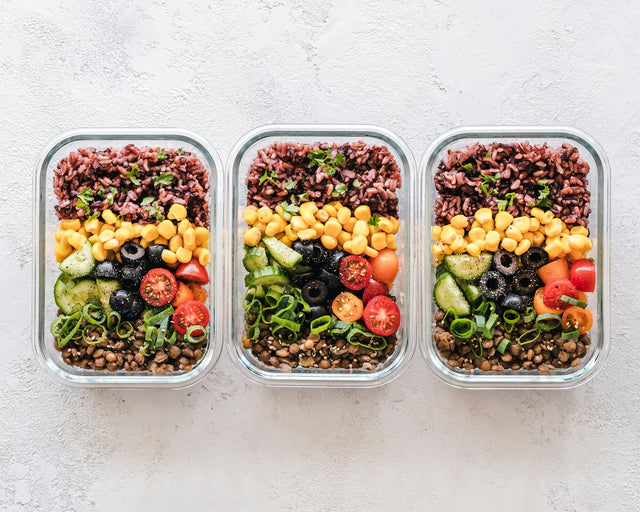 Three glass meal prep containers with colorful layered grains, vegetables, and tomatoes — healthy nutrition for metabolic support