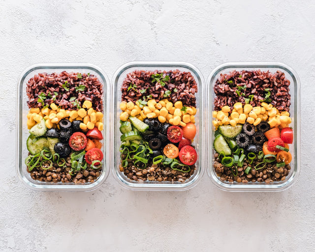 Colorful meal-prep containers with vegetables, grains, and legumes