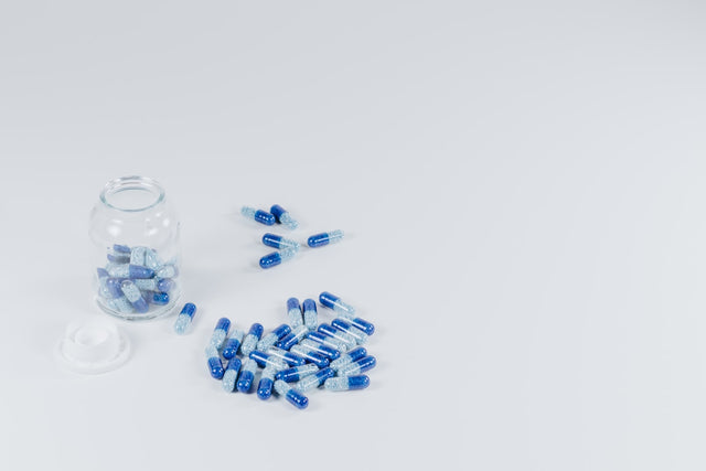white-and-gray pills beside jar with pills