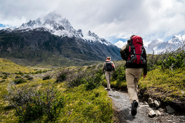 Two people hiking on a mountain trail with backpacks