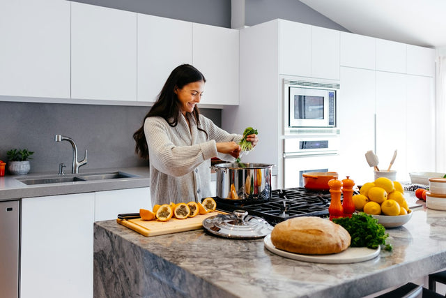 Woman smiling while preparing a healthy meal in a modern kitchen