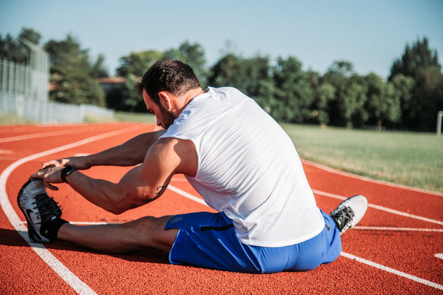 Athlete stretching on a running track for recovery