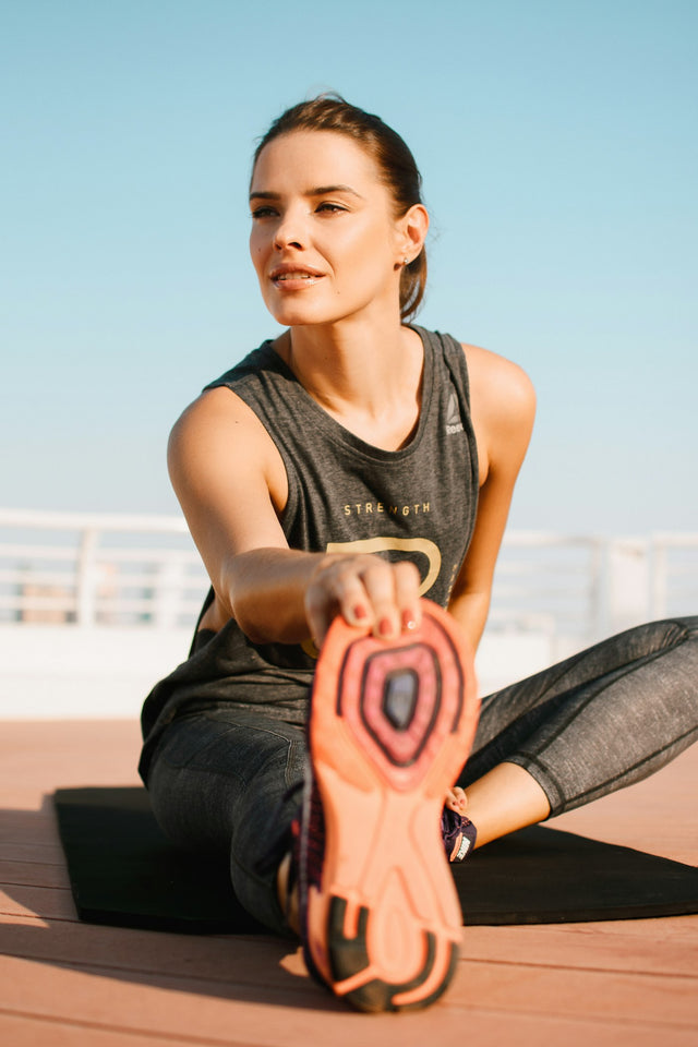 Person in athletic gear stretching outdoors, representing recovery and active wellness