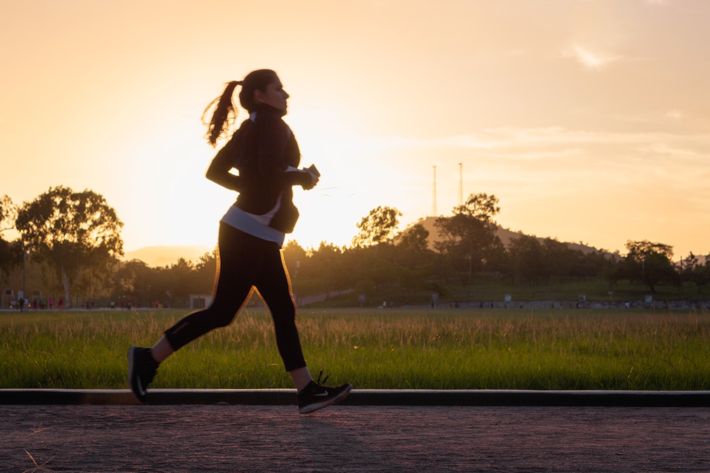 Woman jogging on a park path at sunrise, healthy active lifestyle