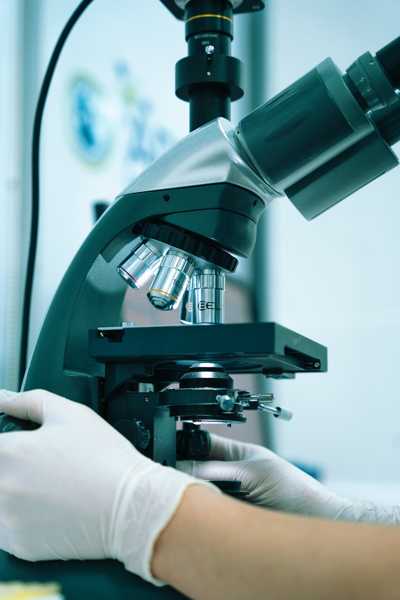Gloved hand operating a microscope in a laboratory