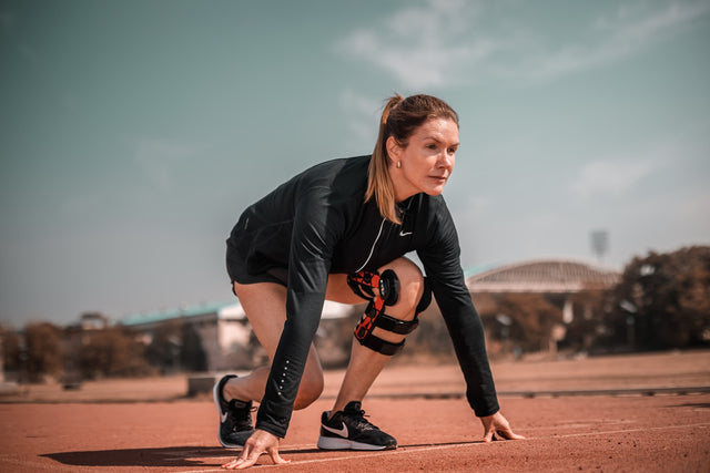 Woman crouching down outdoors, representing an athletic recovery routine