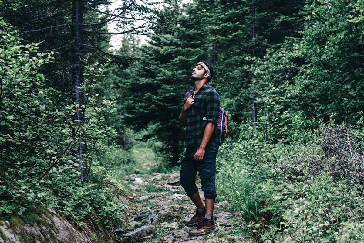 Man with a backpack hiking a forest trail, representing active men's health and vitality