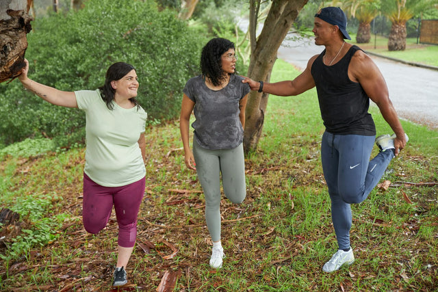 Three friends stretching their legs outdoors before a run, illustrating joint health and recovery