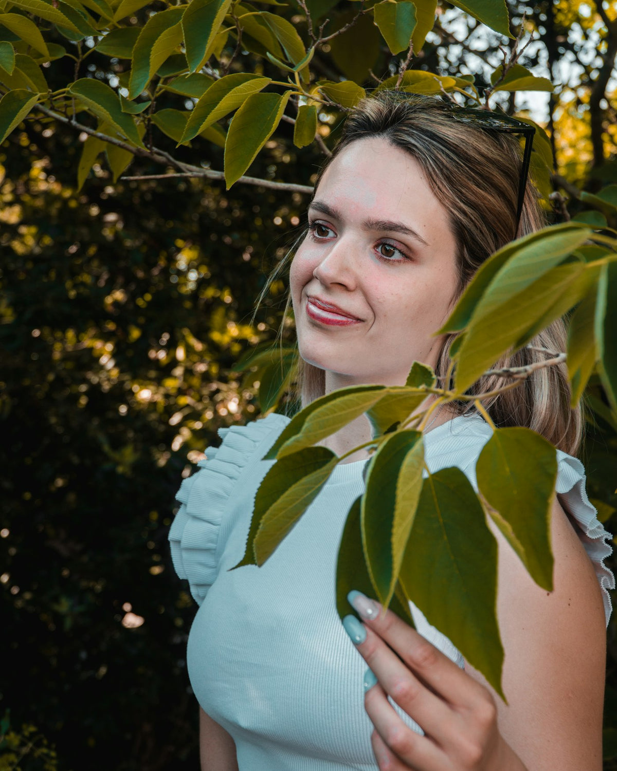 a woman standing under a tree with leaves