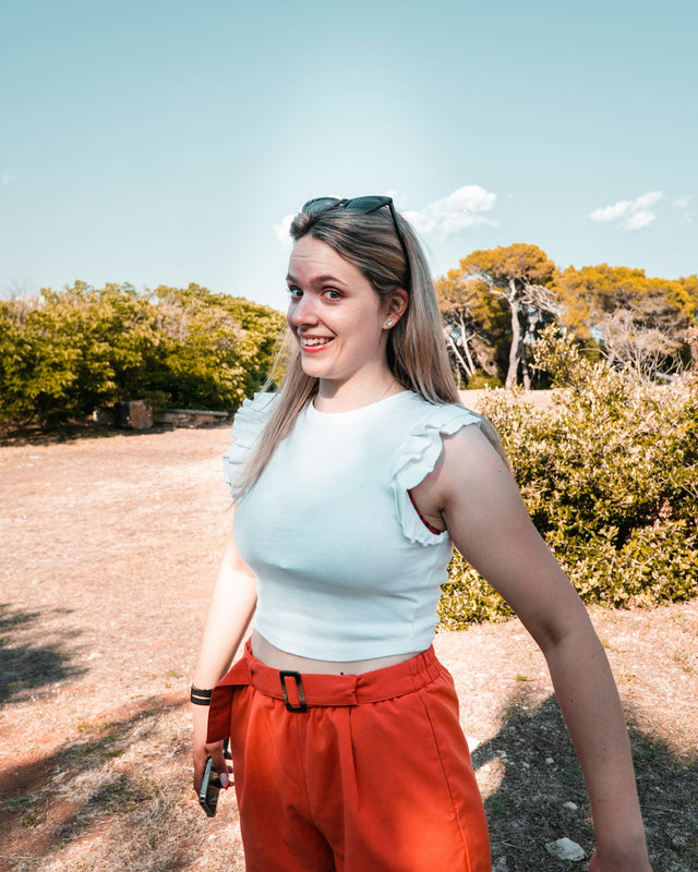 a woman in a white top and orange pants