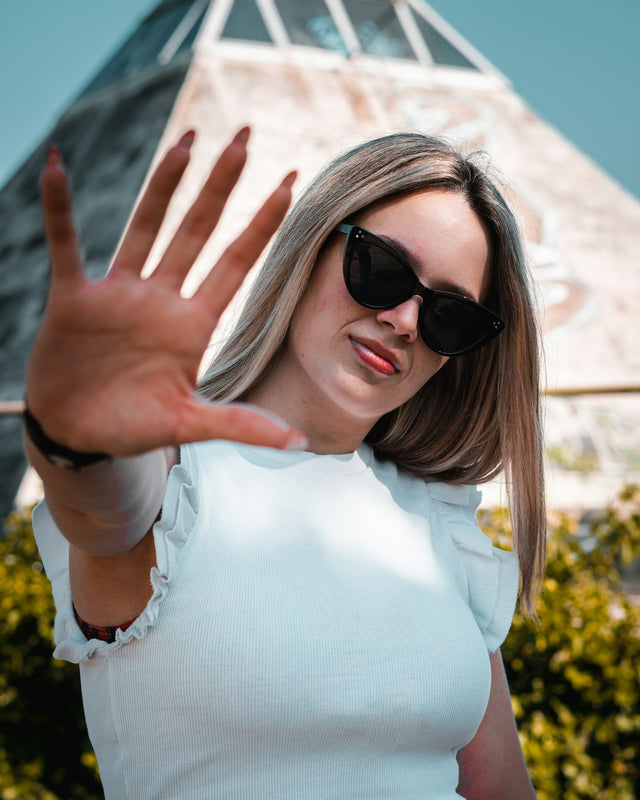 a woman wearing sunglasses making a hand gesture