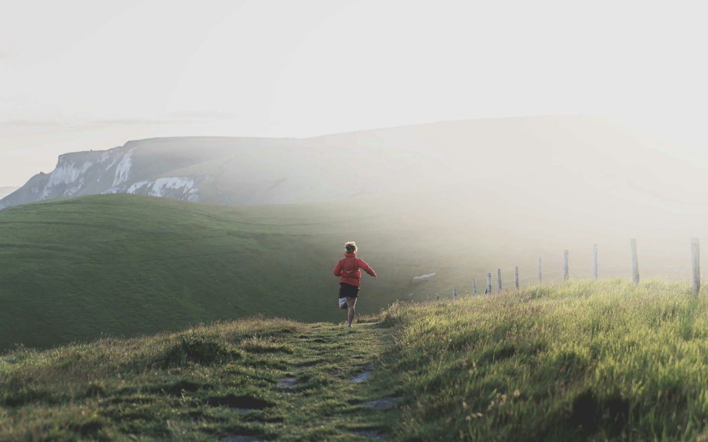 Person running on a misty hillside trail