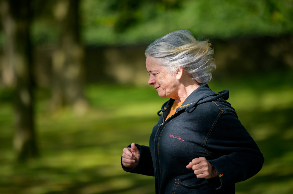 Active older adult woman jogging outdoors in a park — healthy aging and longevity