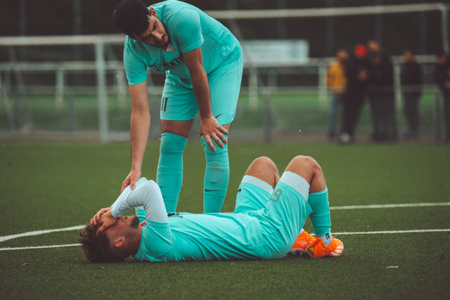 Soccer player lying on the ground after an injury, representing sports injury and recovery