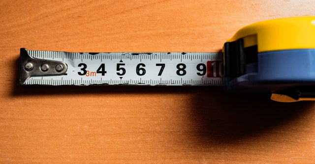 A tape measure on a wooden table, representing weight-loss tracking
