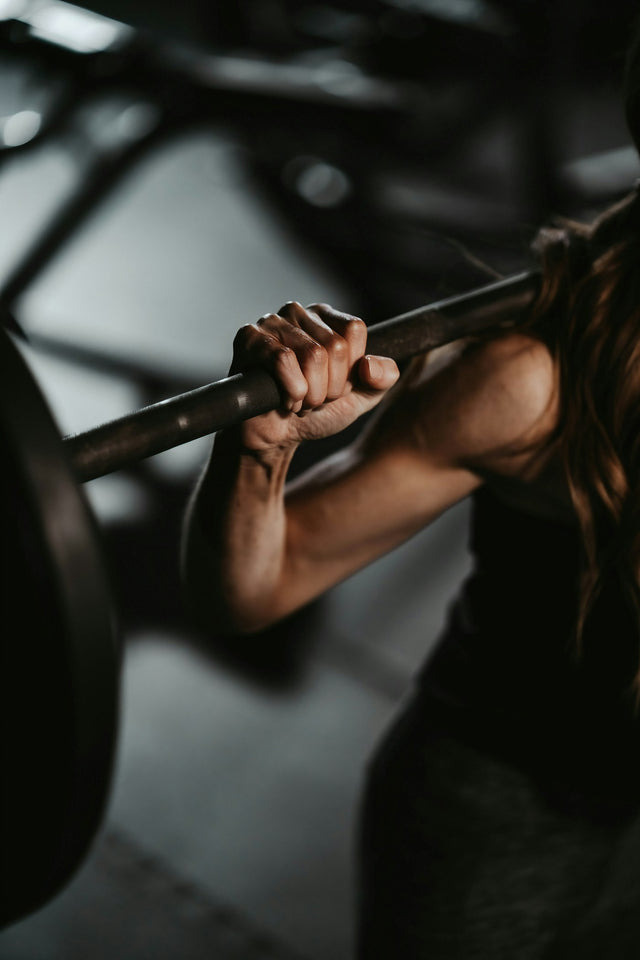 Woman lifting a barbell in a gym, representing fitness and weight loss