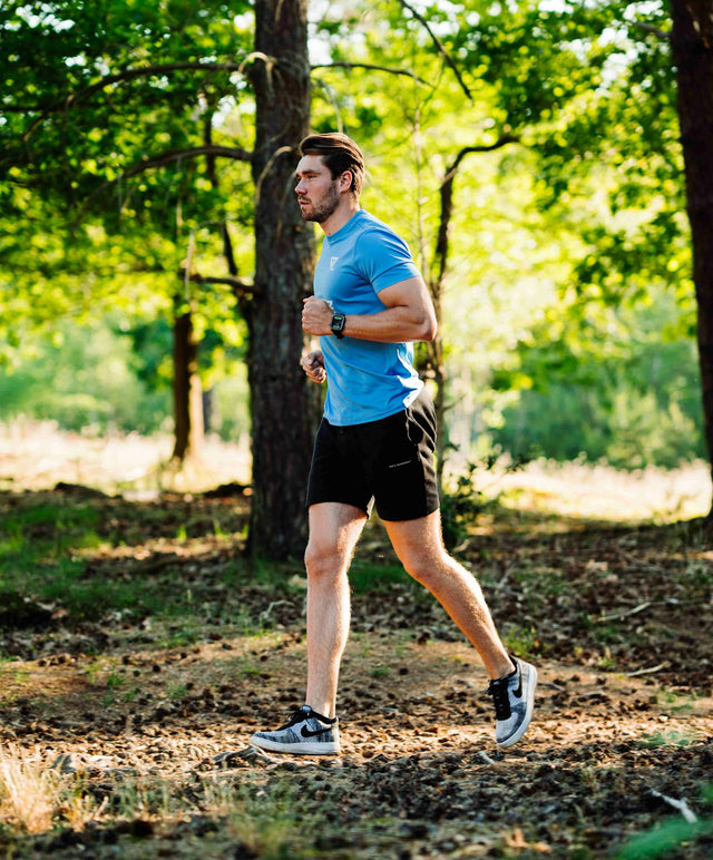 Man running through sunny forest path