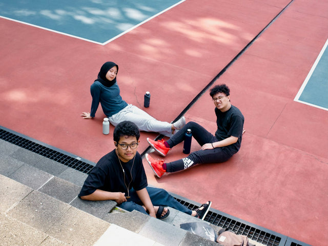 A group of people sitting on a tennis court