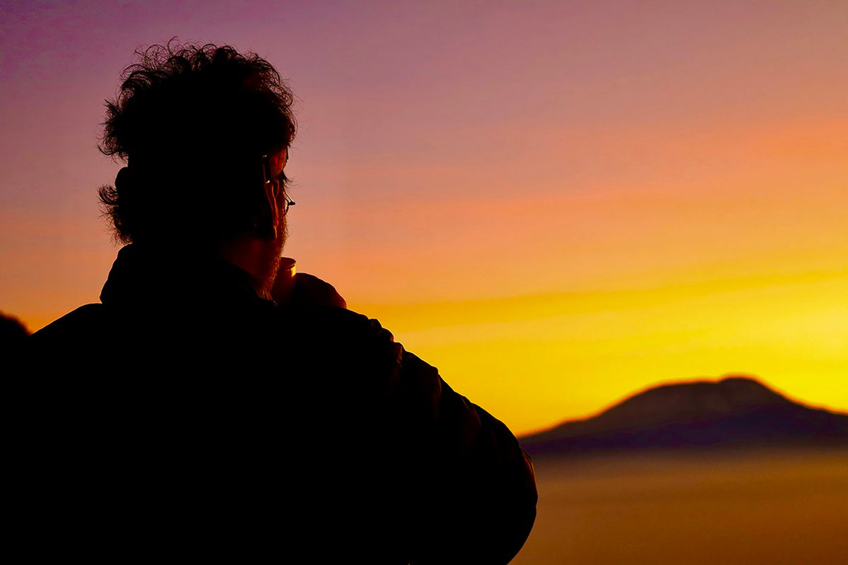Person enjoying a quiet sunrise during a morning wellness routine