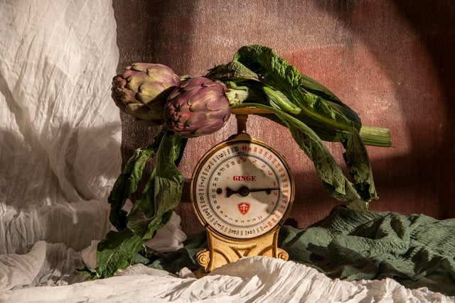 Artichokes rest upon an old-fashioned scale.