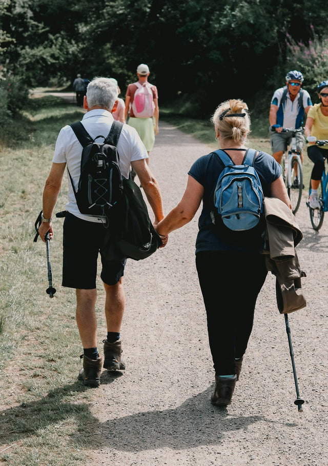 Couple holds hands while walking down a path.