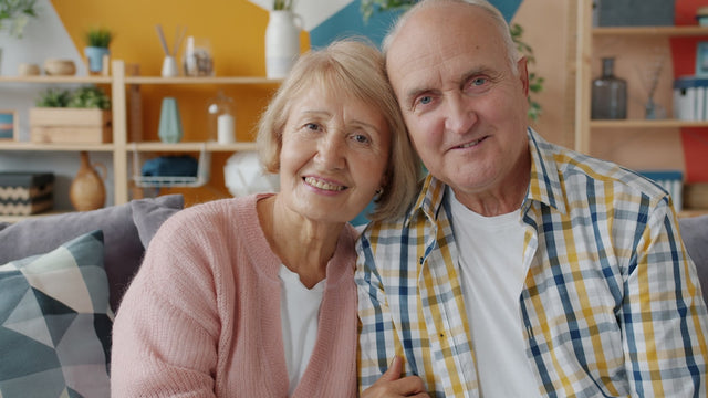 Elderly couple smiling together on a couch.