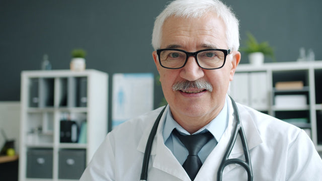 Elderly doctor wearing glasses and stethoscope in office.