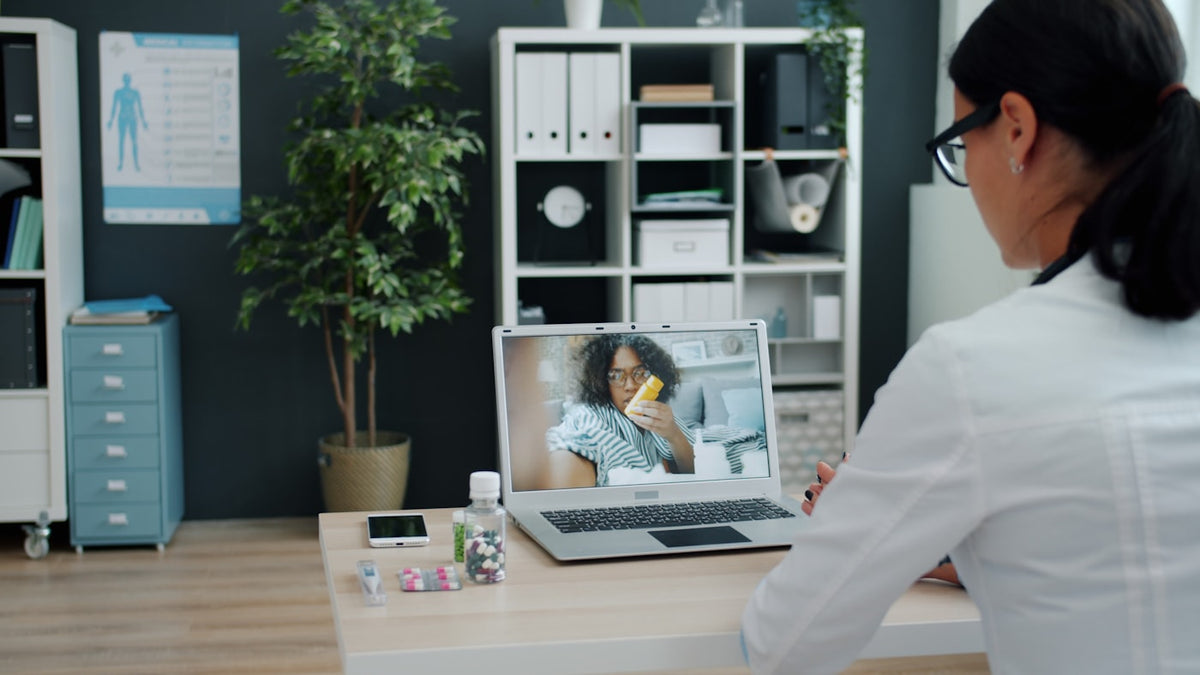 Doctor consulting patient via video call on laptop.