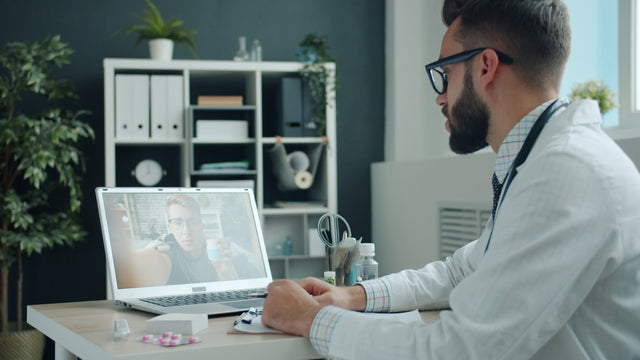Doctor consulting patient via video call on laptop.