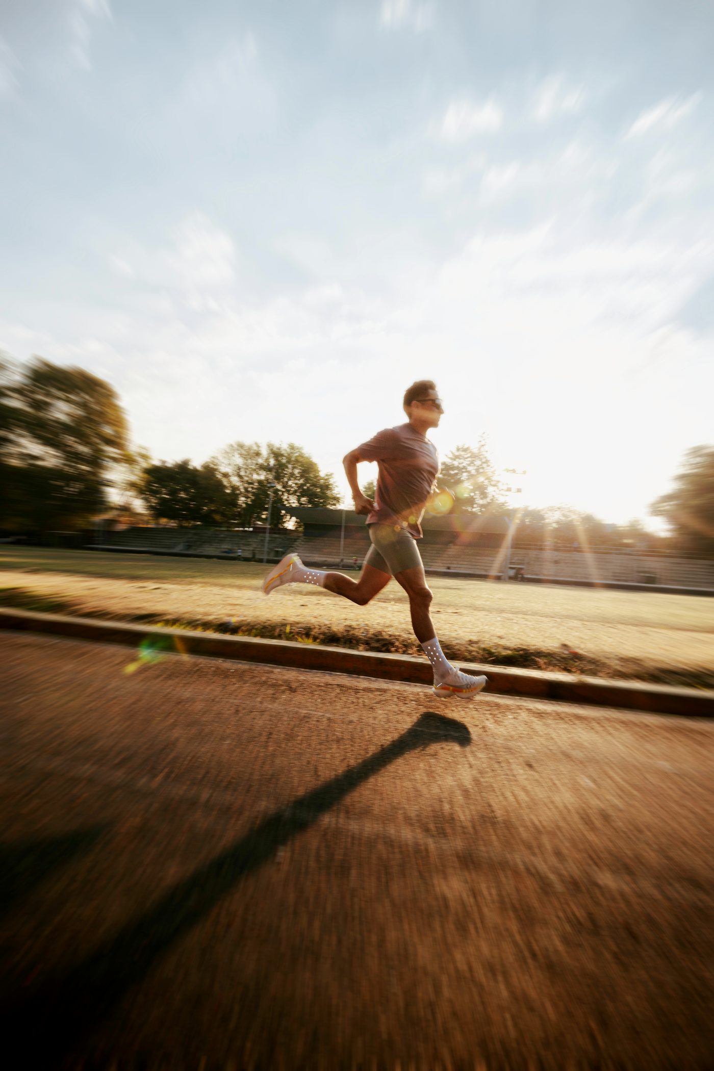Man running on an outdoor track at sunrise — active lifestyle and weight management
