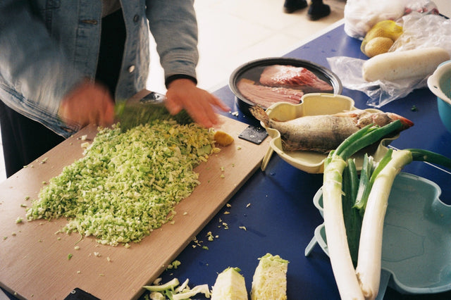 Person chopping fresh vegetables on a wooden cutting board, representing healthy nutrition