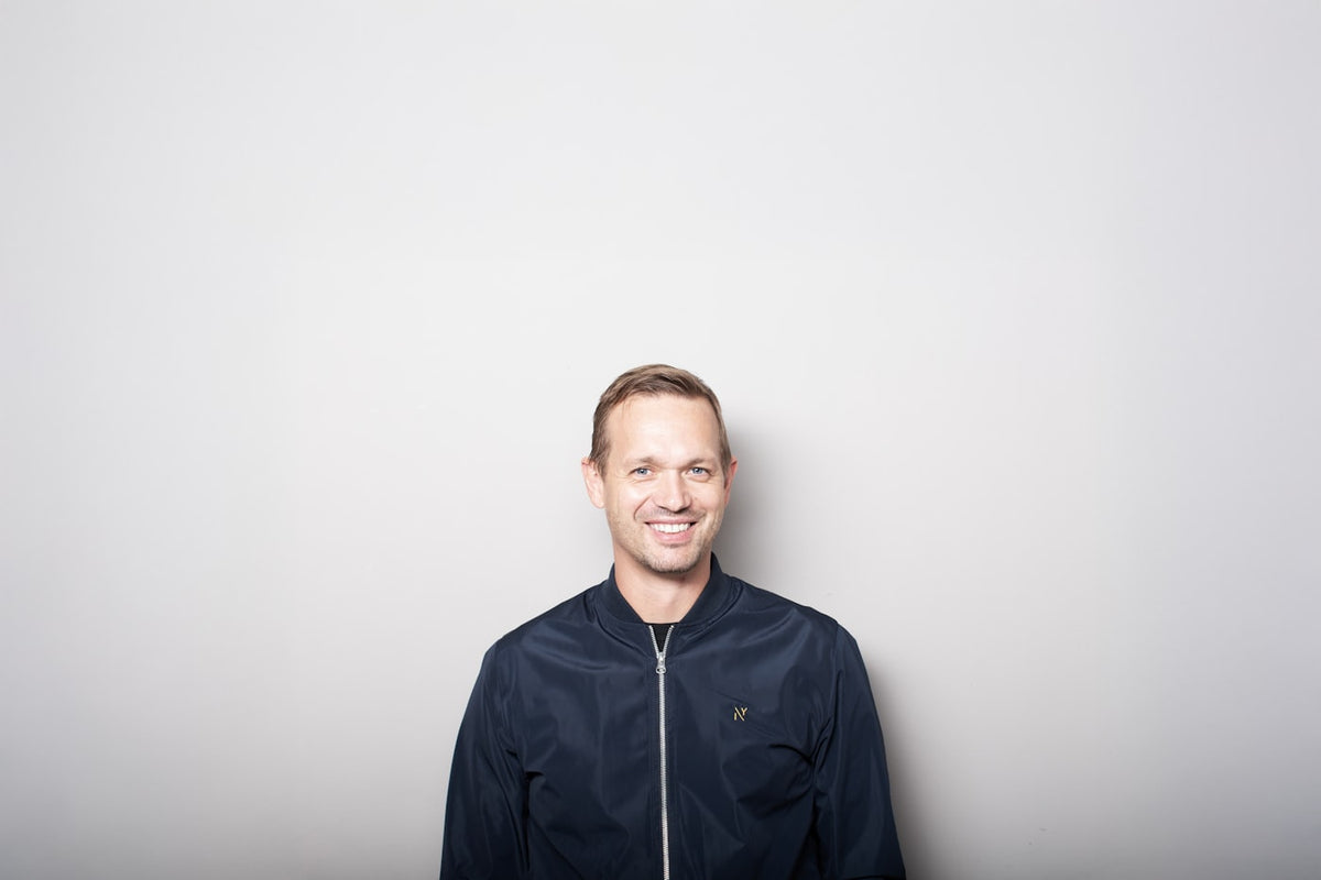 Smiling man in a dark jacket against a gray background