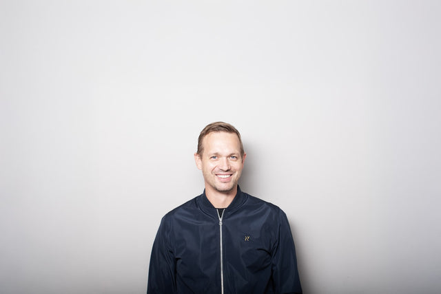 Smiling man in a dark jacket against a gray background