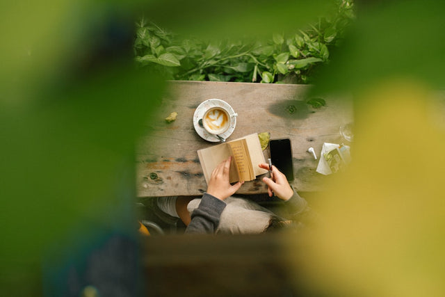 Person reading with morning coffee at a table — focused cognitive wellness
