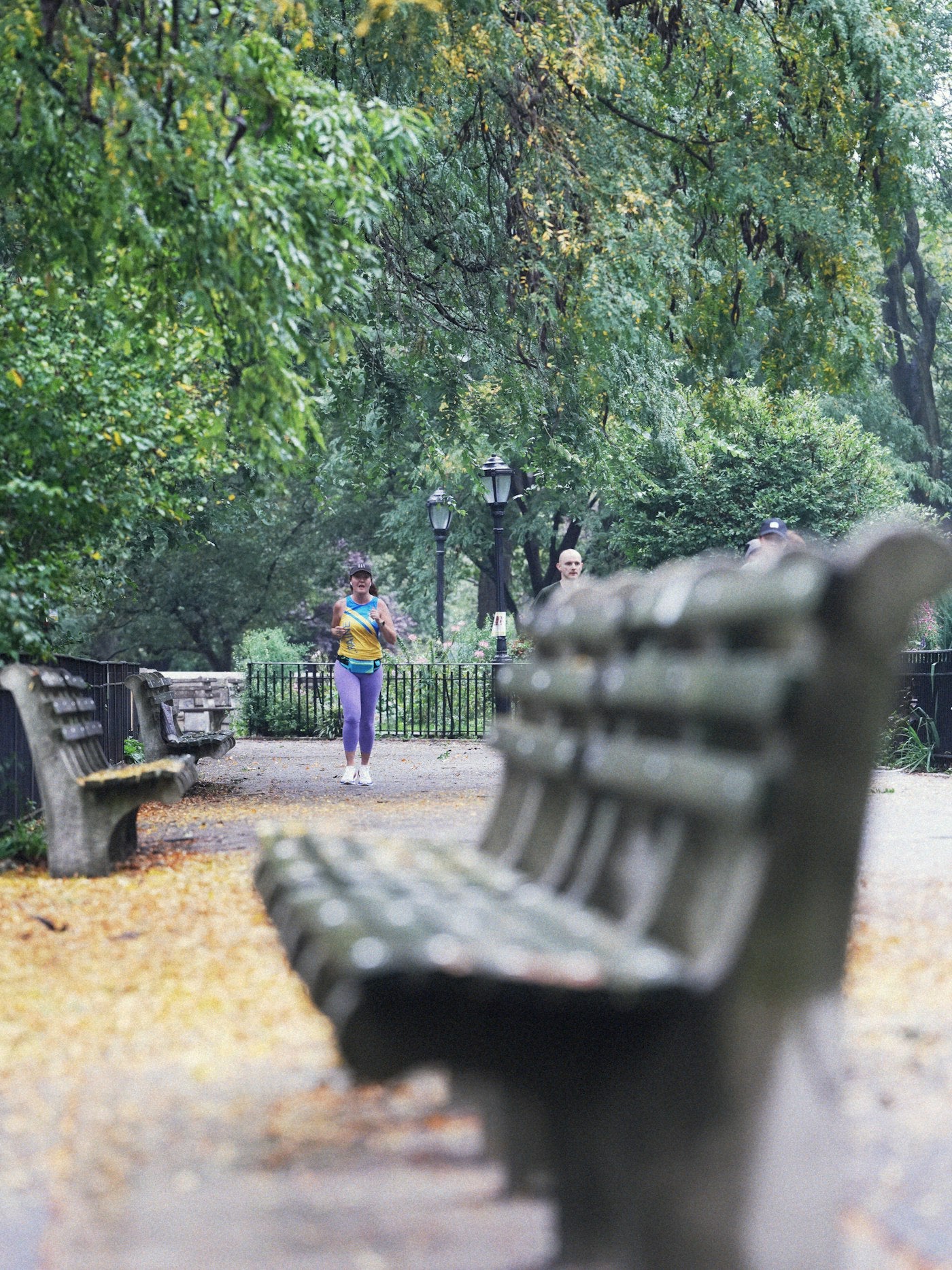 Woman jogging on a leafy park pathway in natural light