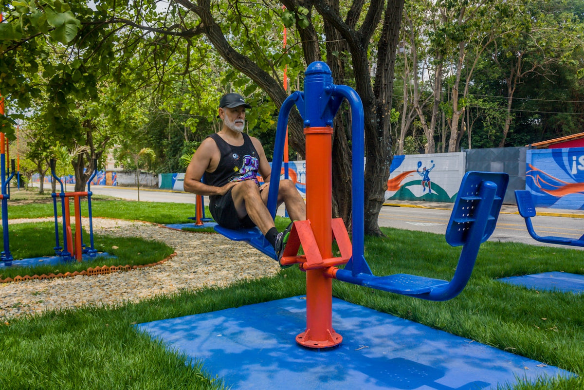 A man exercising on outdoor gym equipment in a park.