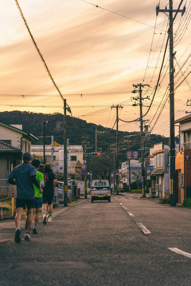Three people running down a street at sunset, representing an active fitness routine