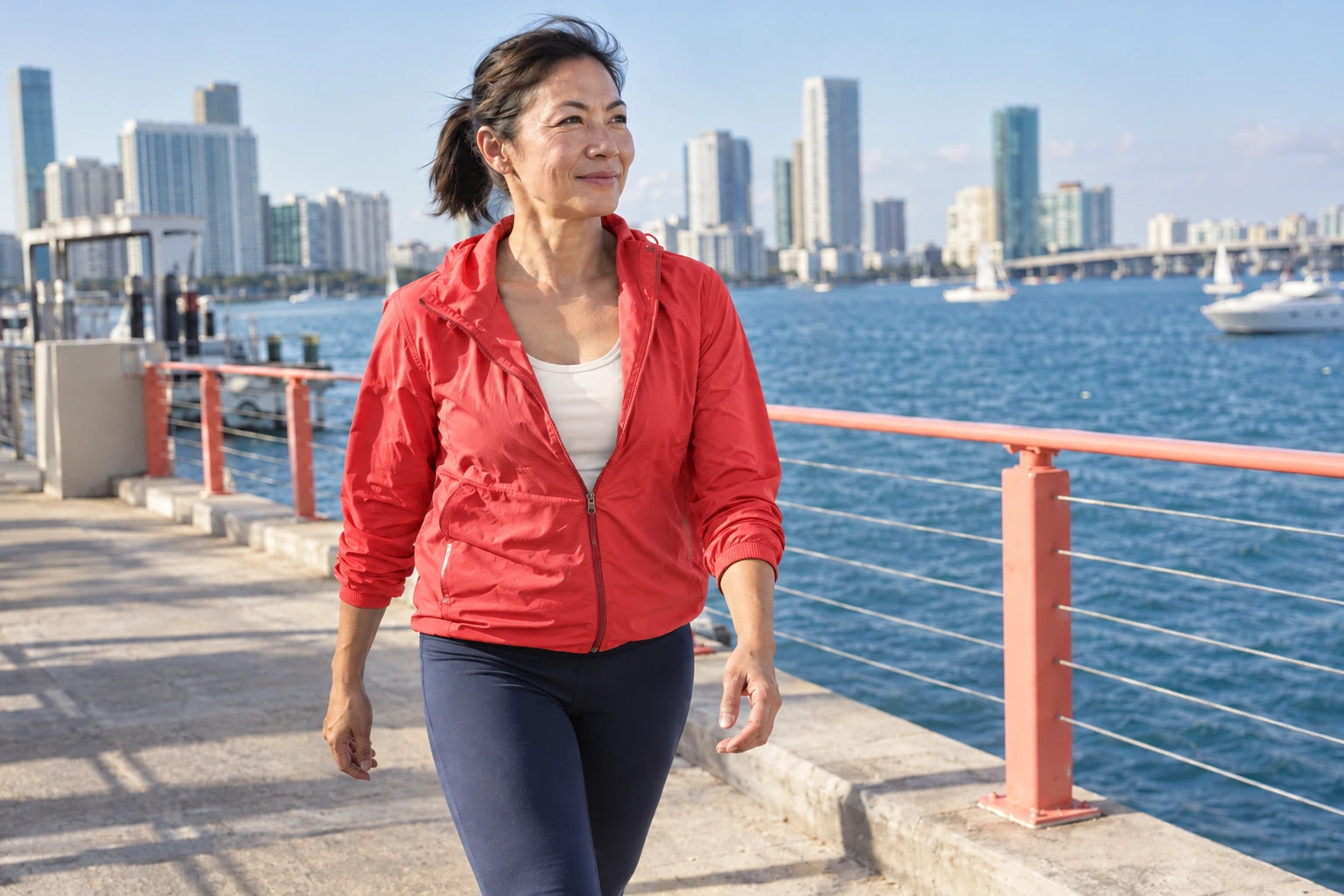 An active woman over 40 walking after a run in a coral jacket